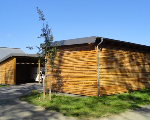 Carports aus Holz mit Bekleidung  aus Holzschwarten mit Rinde, Colpach